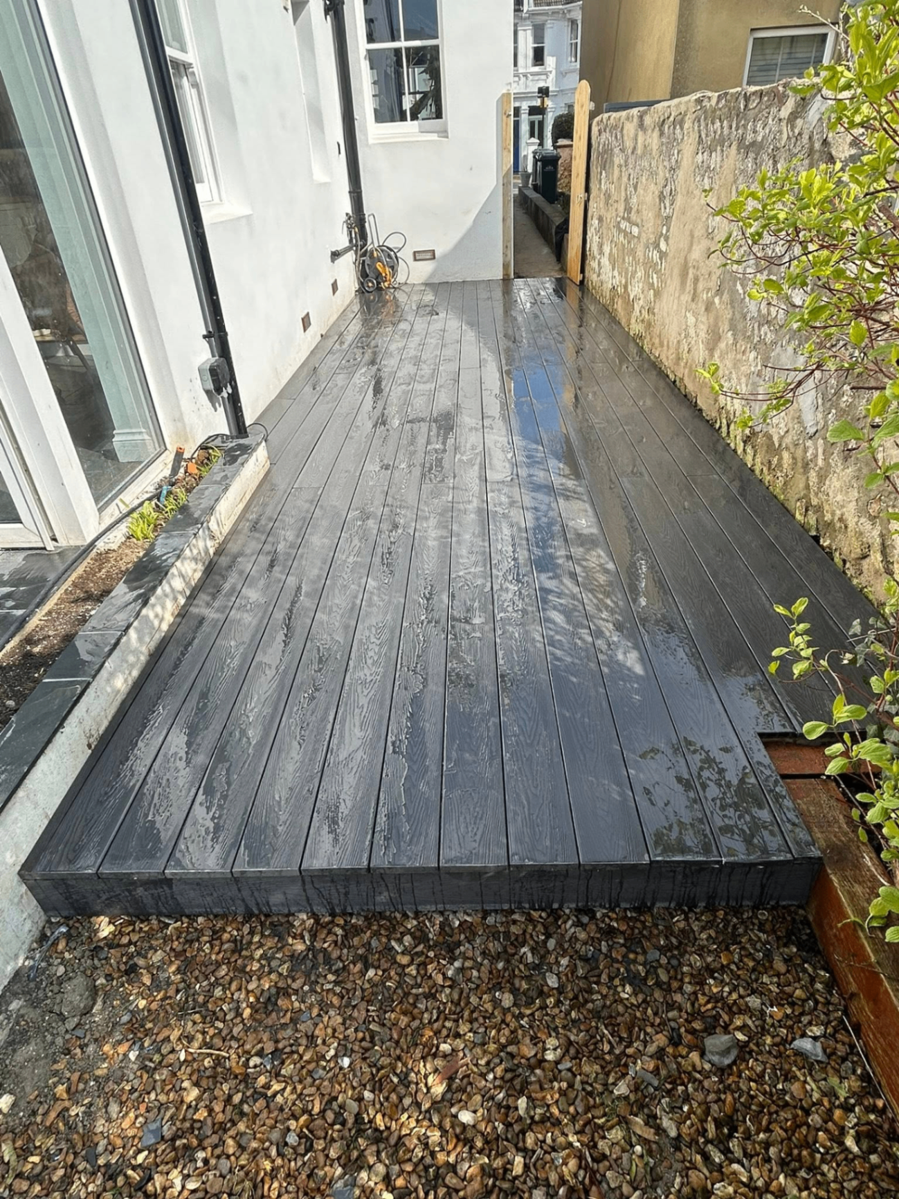 Composite deck in graphite grey laid alongside a Sussex property, freshly hosed and gleaming in the sun.